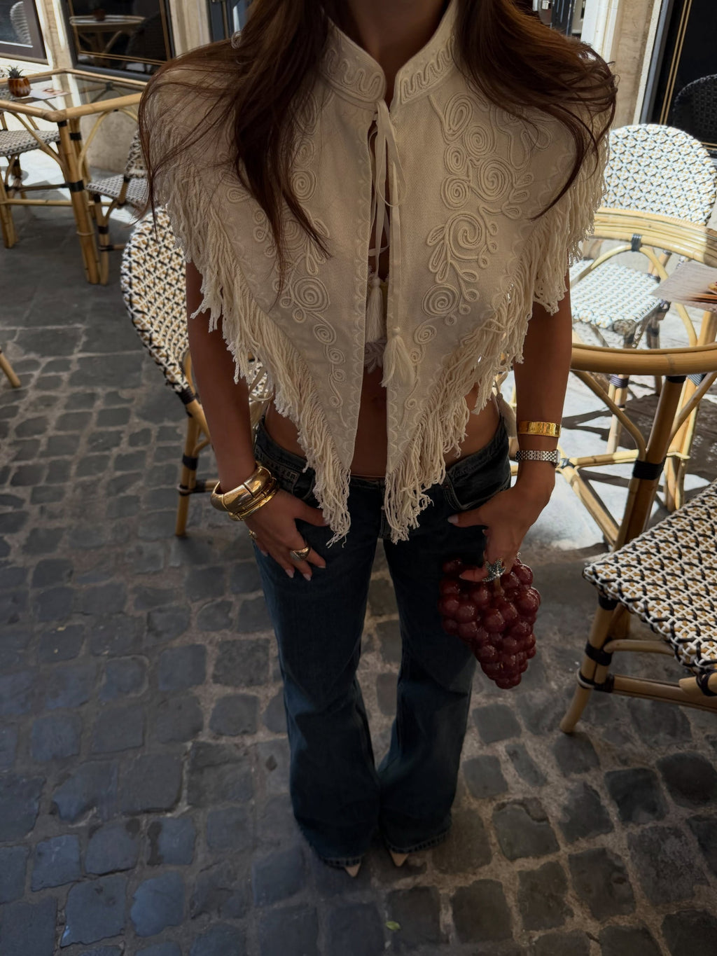 Carlotta Fringe Cape styled with dark flared denim on a terrace